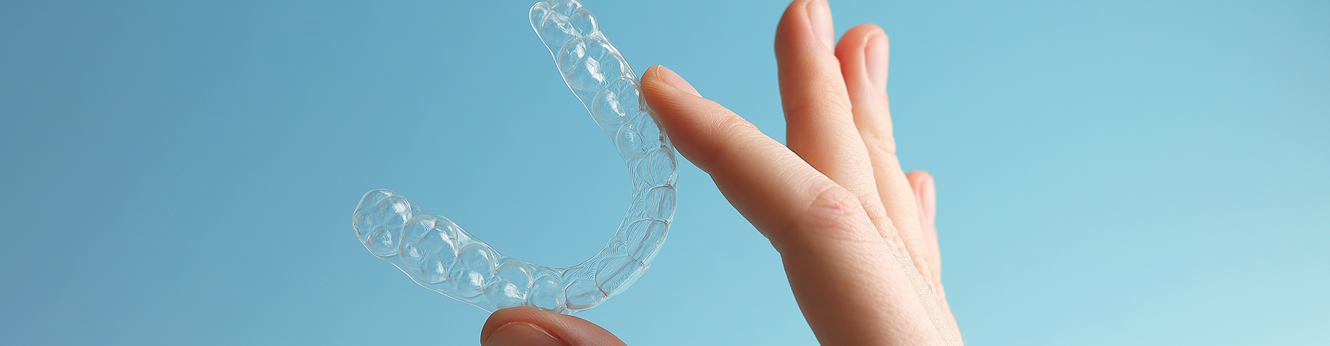 Hand holding clear aligner.
